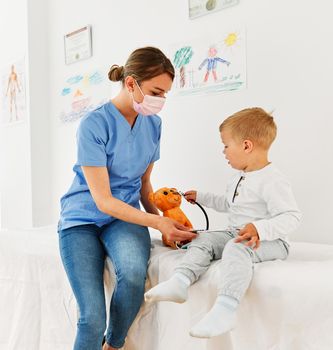 Female doctor or nurse with a little boy in doctor's office in clinic