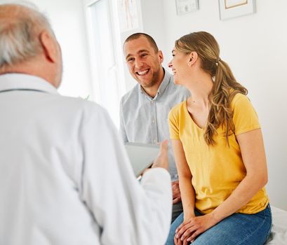 Senior doctor talking to young couple in his office in clinic
