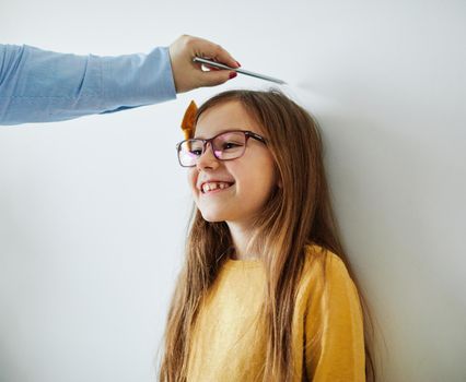 Mother measuring the height of her daughter on the wall at home