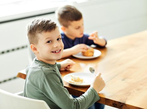 Portrait of two brothers eating cake at home