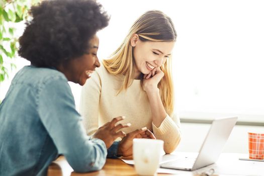 Two young woman using laptop at work in the office or studying at home or in a cafe