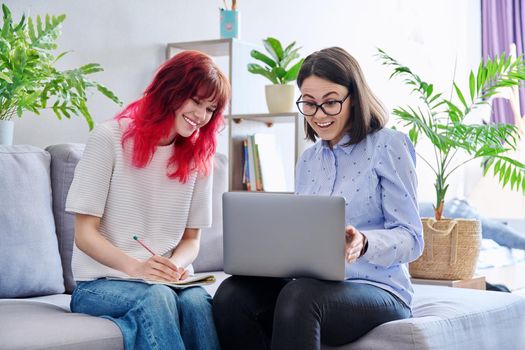 Female teacher teaches student teenage girl, sitting together on couch in office, educational counseling, using laptop. Education, knowledge, individual training, adolescence concept