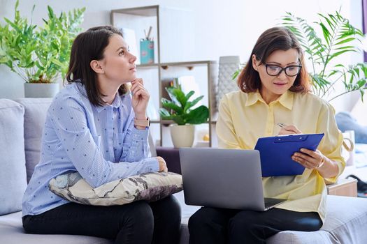 Young woman patient on individual therapy in psychologists office. Mature female counselor listening taking notes talking. Psychology, psychiatry, treatment, mental health concept