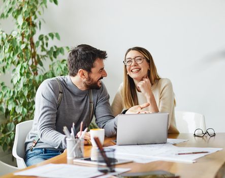 Portrait of young business people having a meeting in the office, having fun together and laughing