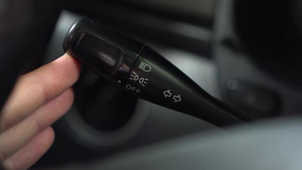 A man turns on the turn signal to the right on the lever in the car. Automotive panel close-up. 4k