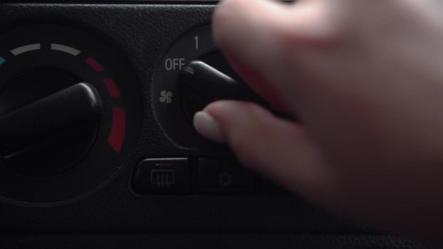 The woman turns on the fan and presses the air conditioner button in the car. Automotive panel close-up. 4k