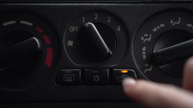 The woman turns on the fan and presses the button for the internal ventilation in the car. Automotive panel close-up. 4k