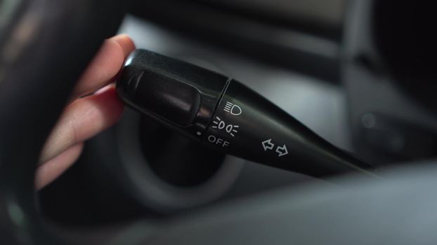 A man presses several times on the high-beam lever in the car. Automotive panel close-up. 4k