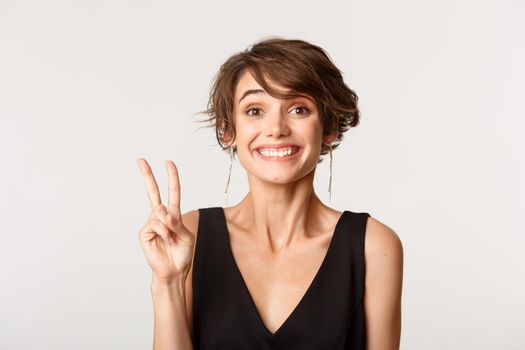 Close-up of cheerful attractive woman showing number two and smiling.