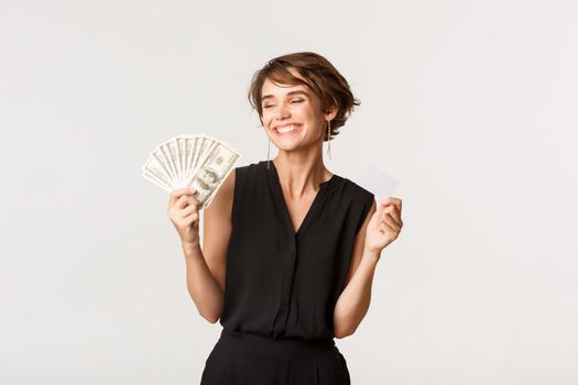Successful elegant woman smiling pleased, showing money and credit card.