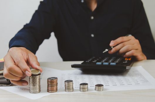 Male hands holding coins and paper documents calculator.Business economic finance tax and investment concepts.