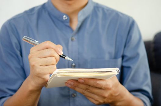 Businessman holding a pen and a notebook to take notes and plan ideas.