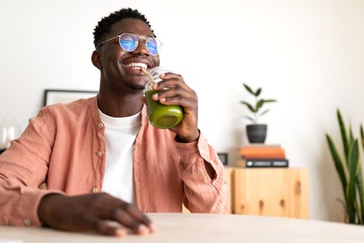 African American black man drinking healthy green juice with bamboo straw looking at camera. Copy space. Wellness and healthy lifestyle concept.