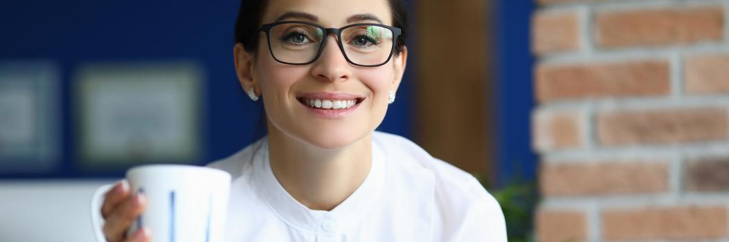 Portrait of attractive brunette businesswoman at work with cup of coffee read report. Smiling positive energy from boss. Business, morning routine concept