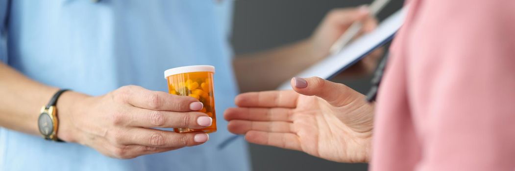 Close-up of female doctor in uniform give container with medication to patient. Qualified specialist advice drug for treatment. Medicine, pharmacy concept