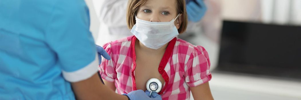 Portrait of pediatrician doctor with stethoscope tool listen kids breath and heartbeat. Calm little girl sit in office and get checkup. Medicine concept