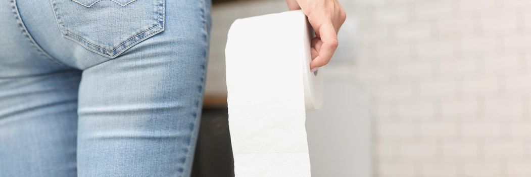 Close-up of woman hold toilet paper roll in hands, came to toilet room. Constipation or diarrhea problem, nature calls. Hygiene, bathroom, restroom concept