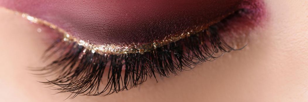 Close-up of pretty makeup on woman face, red autumn colours. Macro shot of bright eye shadow any festive celebration. Mua, beauty, makeup, artist concept