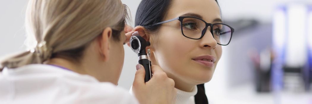 Portrait of doctor check patients ear on medical examination with special tool. Appointment in clinic at otolaryngologist specialist. Healthcare concept