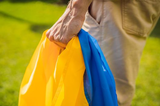 A man holds a Ukrainian flag in his hands. concept Ukrainian patriot, rally in support of Ukraine.