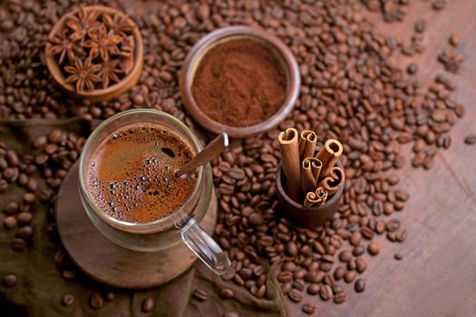 Tasty steaming espresso in cup with coffee beans. View from above. Dark background.