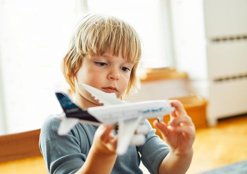 Portrait of a little boy playing with airplane model toy at home