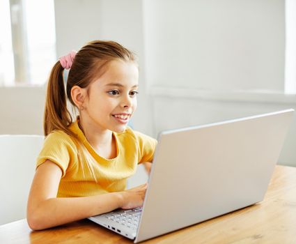 Portrait of a little girl having fun using laptop or doing homework with laptop at home