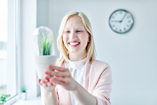 portrait of a young business woman holding a plant under glass in the office