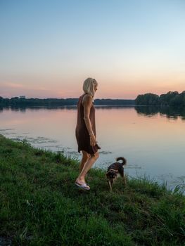 Beautiful woman enjoys holidays at sunset near river