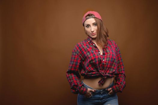 Sexy young caucasian woman in a plaid shirt on a brown background. Studio photography.