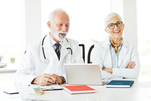 portrait of a senior doctors with laptop sitting on their office