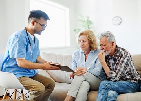 Doctor or nurse caregiver with senior couple using tablet at home or nursing home