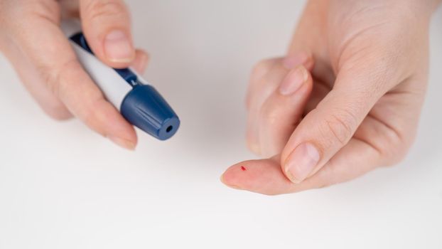 Caucasian woman doing a glucose test using a pen lancet