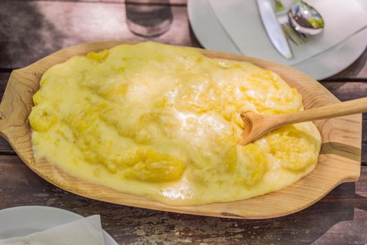 Traditional Montenegrin Meal. Kacamak in wooden bowl in the outdoor cafe.