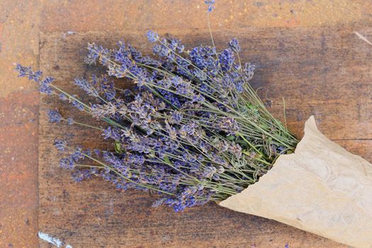 Bouquet of lavender in paper packaging. Lavender flower bouquet on old rustic wooden background. Flatlay french provence style flower blossom. Lavender aromatherapy. Drying lavender flowers