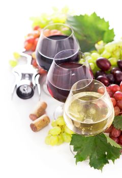 glasses of red and white wine and ripe grapes on table