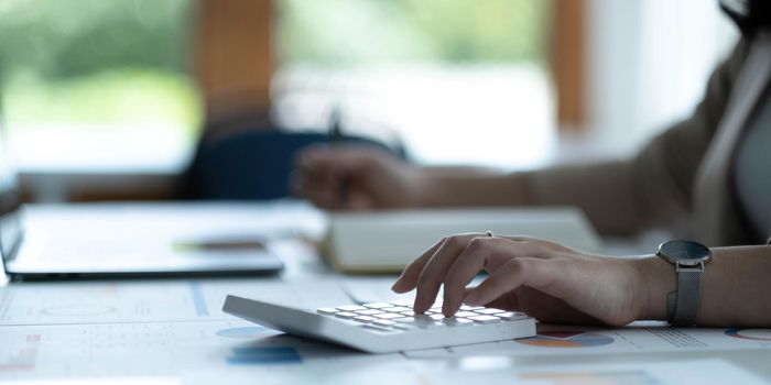 Close up Business woman hand using calculator to calculate the company's financial results and budget. Account Audit Concept..