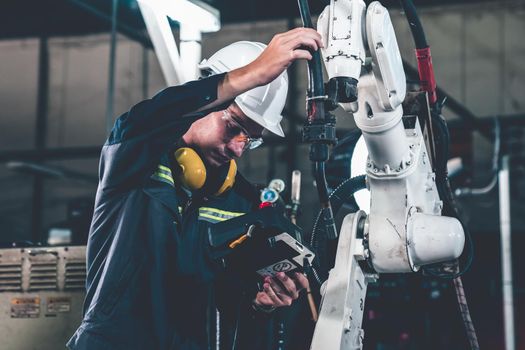 Young factory worker working with adept robotic arm in a workshop . Industry robot programming software for automated manufacturing technology .