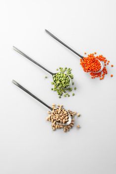 3 spoons on white background with Ancient grain food. Useful food for those who are on a diet and watching their health. red Lentils and green peas on white beans black eyes