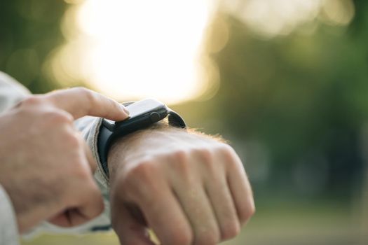 Smart watch. Smart watch on a man's hand outdoor. Man's hand touching a smartwatch. Close up shot of male's hand uses of wearable smart watch at outdoor in sunset.