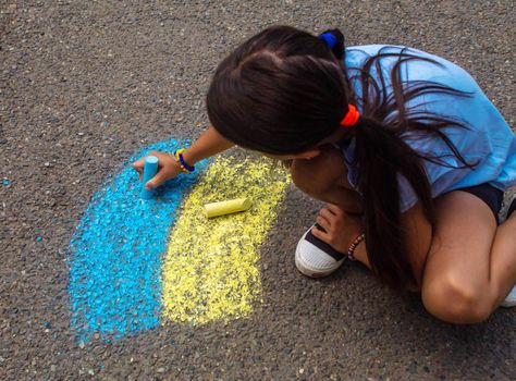 Children draw the Ukrainian flag house on the pavement. Selective focus. child