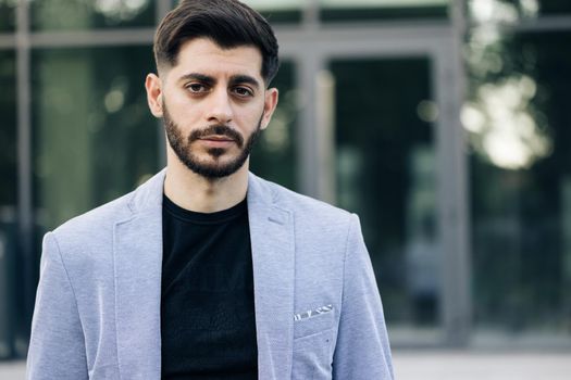 Caucasian bearded young man in formal outfit looking to camera outside on street. Feel happy businessman portrait business beautiful modern manager pretty