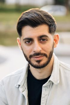 Close up of face bearded handsome man looking at camera serious attractive beautiful male stand on street city lifestyle summer guy city outdoors.