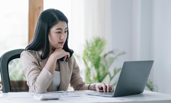 Asian woman working on a laptop computer,Working in the office with laptop concept,Young Asian woman starting a business using a laptop computer..