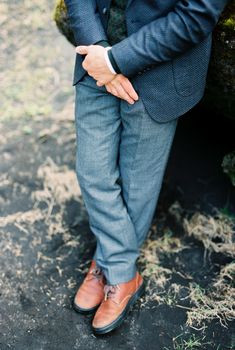 Man in a blue suit and brown boots leaned against a rock. Close-up. High quality photo