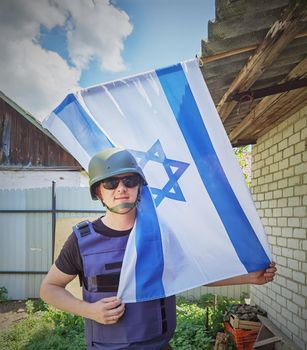 Israeli soldier holds the flag of Israel in front of him. Concept: Israel Memorial day, Holocaust Remembrance Day, Independence Day in Israel