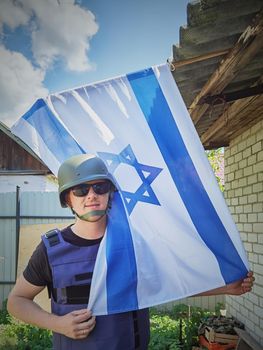 Israeli soldier holds the flag of Israel in front of him. Concept: Israel Memorial day, Holocaust Remembrance Day, Independence Day in Israel