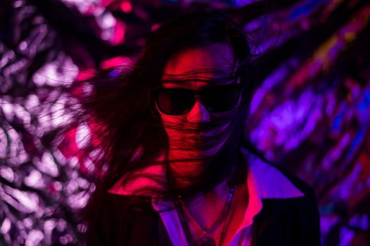 Portrait of a transgender model in sunglasses in a studio with neon lighting