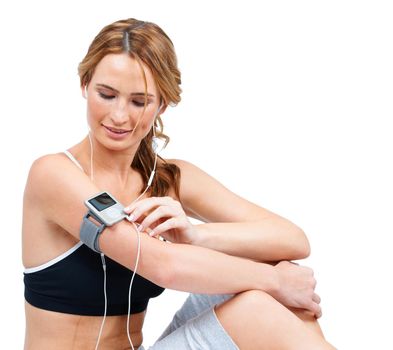 A fit young woman adjusting an mp3 player attached to her arm while taking a quick breather.