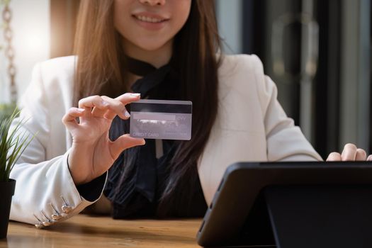 Asian young woman using a tablet and credit card for online shopping.